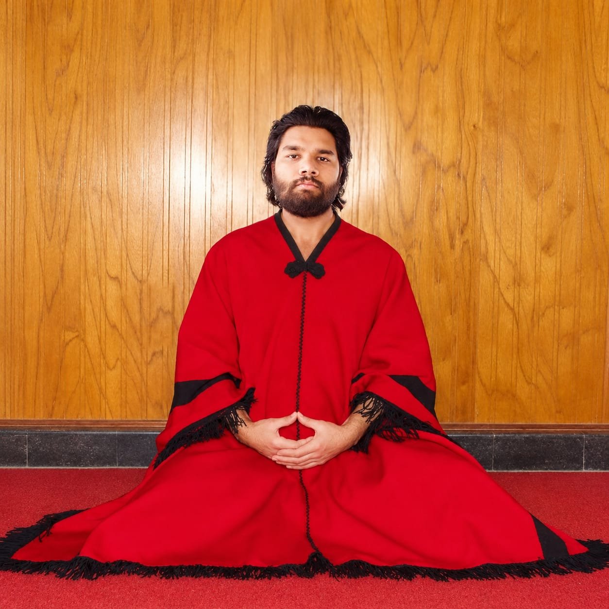 Teacher Humayun Javed sitting in meditation wearing a red robe